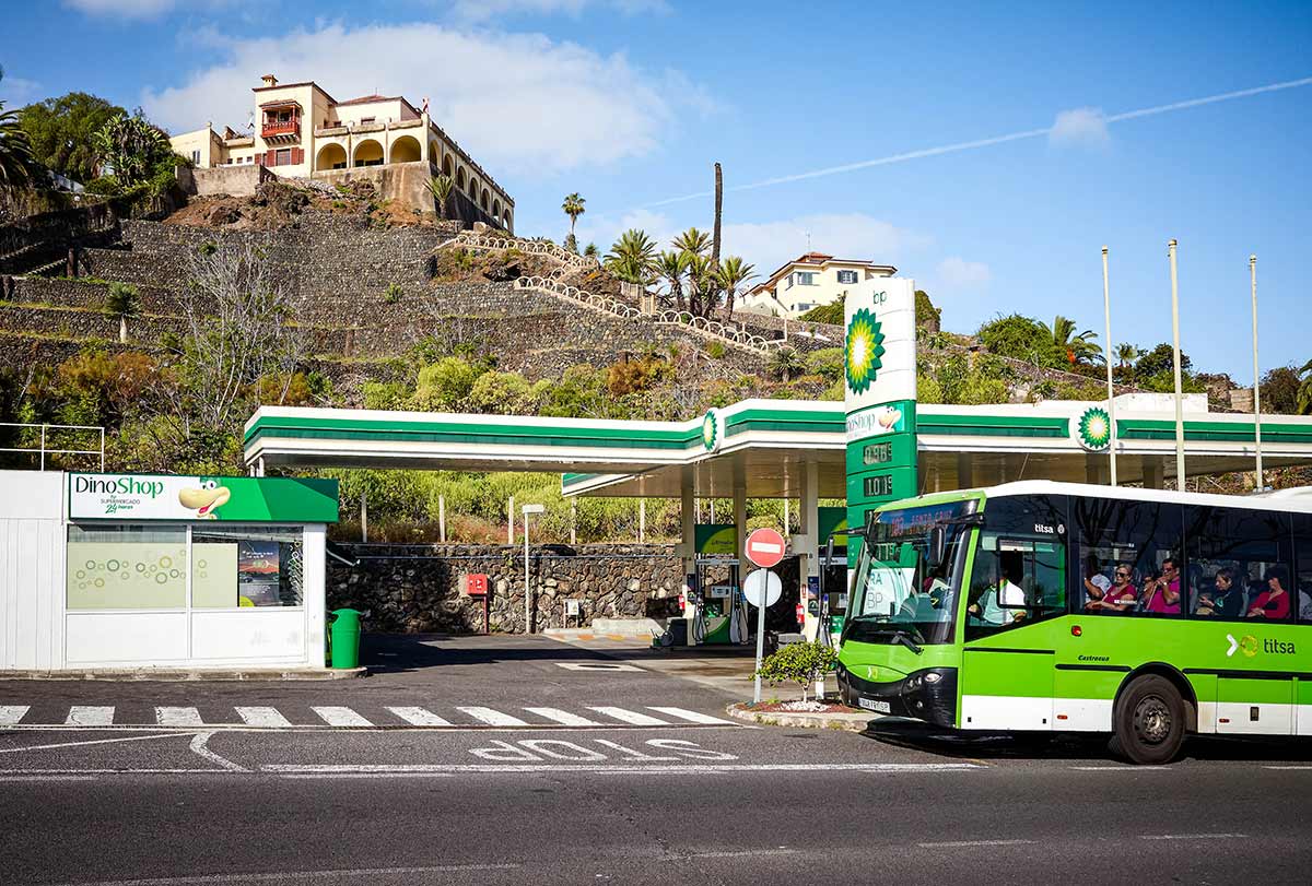 Green bus passing gas station